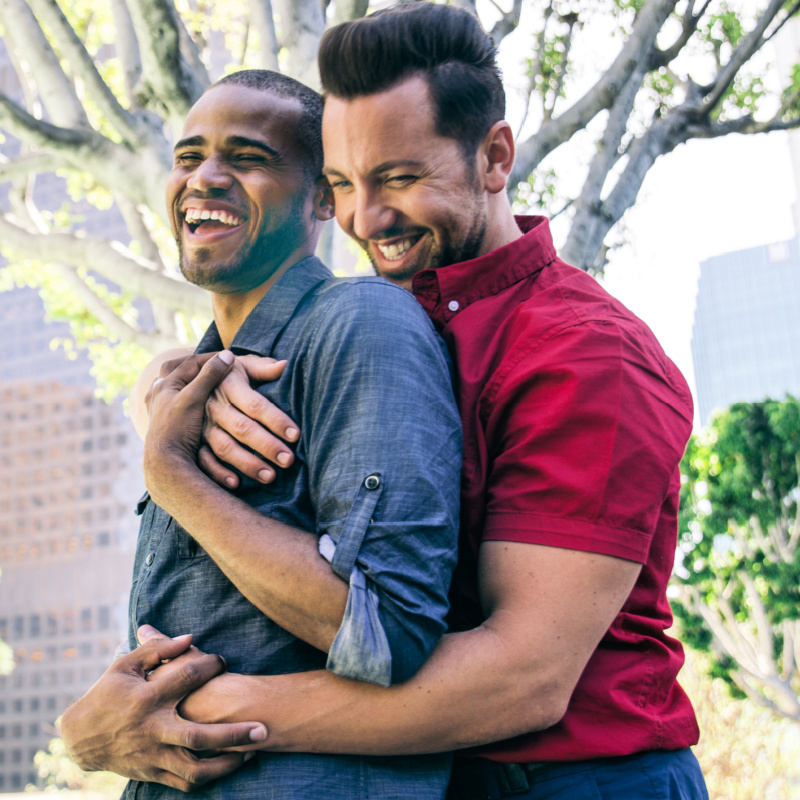 LGBTQ couple laughing together and hugging.