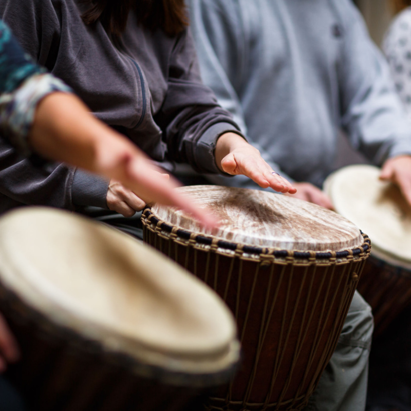 A group of individuals playing a variety of drums in a drum circle.