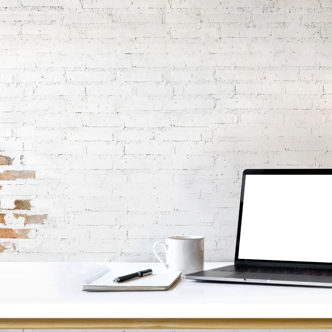 A laptop, notebook, and mug sitting together on a desk.